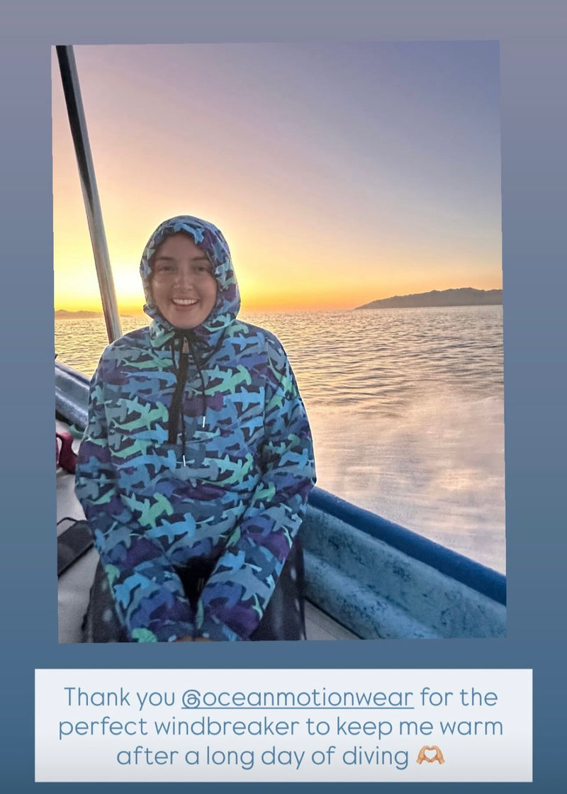 Person wearing a colorful hooded jacket on a boat with a sunset background